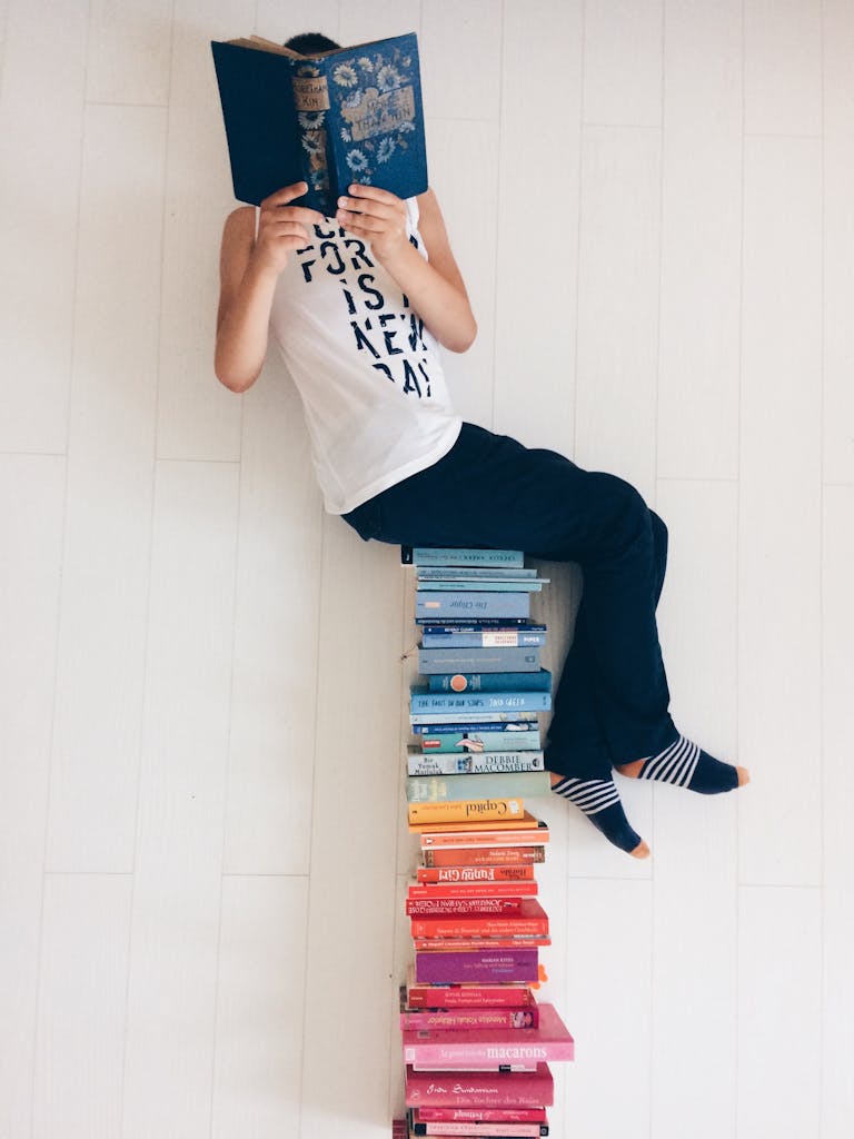 A Person Sitting on a Stack of Books and ReadingĀ